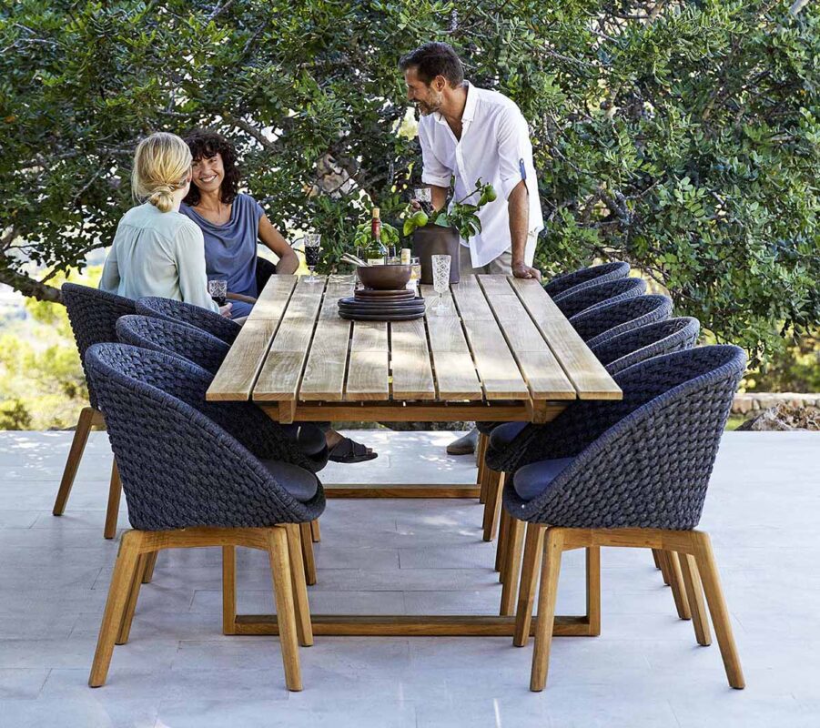 Miljöbild på Peackock karmstol med matbordet Endless i teak från det danska varumärket Cane-Line