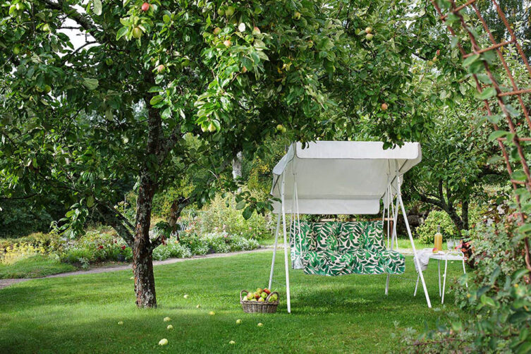 Miljöbild på Duo hammock i vitt med gröna dynor.